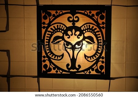 Metal forging. Decorative element. Metal grill. Lighting on the wall. Head of a goat made of metal decoration. Blacksmiths art