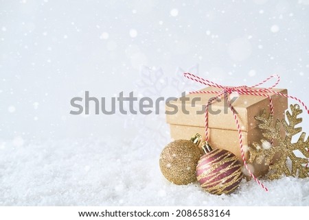 Craft gift box, Christmas balls and a snowflake on a light background with lights. Christmas festive background. Place for your text. Abstract picture with a festive new year mood.