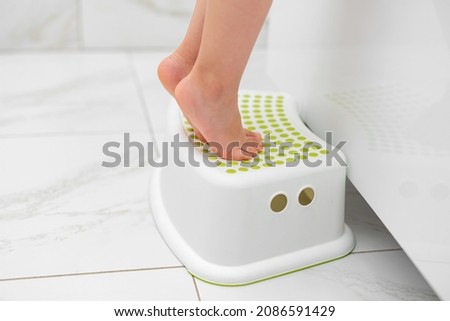 Small legs stand on a special children's bath stand.