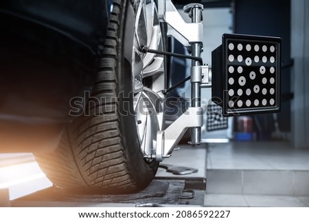 CLose-up car wheel indoors service maintenance repair center against laser sensor equipment diagnostics and 3d wheel alignment. Vehicle inside garage workshop for auto camber toe check fixing work Royalty-Free Stock Photo #2086592227