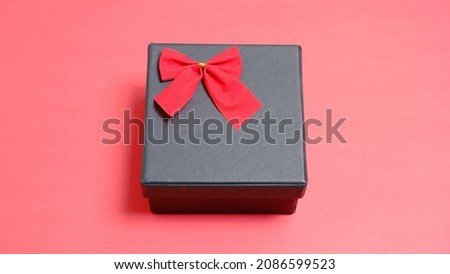 Black gift box with red ribbon on red background. Christmas and new year concept, Valentine Concept. Copy space, Negative Space. High View.