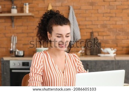 Young woman with laptop in kitchen