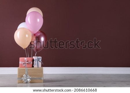 Many gift boxes and balloons near brown wall. Space for text
