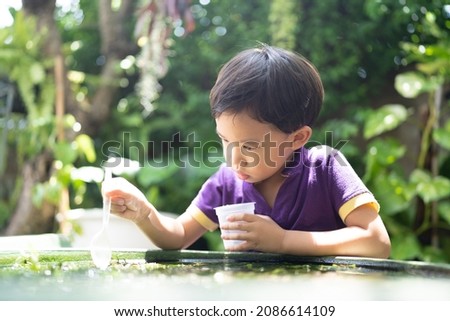 Boy feeding fish in a little garden.