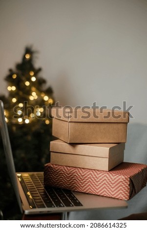Female hand holding a black plastic bank card on a background of gifts box over the keyboard a laptop. Christmas shopping online at home. High quality photo