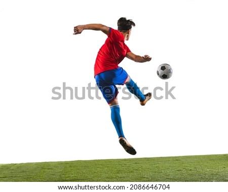 Back view photo of young soccer football player kicking a ball with his leg. Man training in uniform on grass flooring white background. Concept of action, team sport game, energy. Copy space for ad. Royalty-Free Stock Photo #2086646704