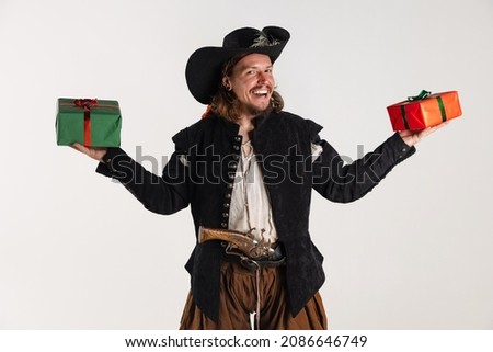 Giving presents. Portrait of man, pirate in vintage costume holding two gift boxes isolated over white background. Combination of medeival and modern styles. Concept of history. Copyspace for ad.