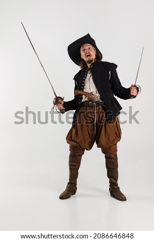 Portrait of brutal, frightening man, pirate in vintage costume raising swords isolated over white background. Combination of medeival and modern styles. Concept of history. Copyspace for ad.