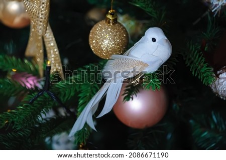 White bird on the Christmas tree, glass ball, beautiful yellow bokeh. Shallow depth of field. The artistic intend and the filters. Airy atmosphere. Toned image.