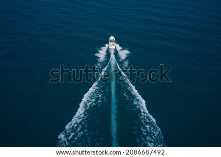 Travel on high-speed boats on the water. Large white boat on the water in motion top view. Luxury motor boat on dark blue water aerial view. Speedboat with people fast moving on dark water.