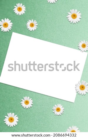 Flatlay of aesthetic styled invitation template. Blank paper sheet card with chamomile flower