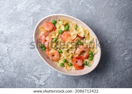 Top view of tasty italian farfalle pasta with shrimps or prawn and green peas on grey concrete background Royalty-Free Stock Photo #2086712422