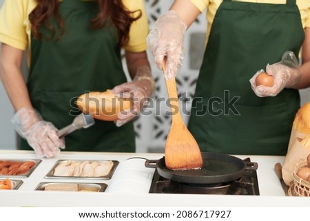 Cropped image of vendors frying eggs when making sandwiches at street food cart Royalty-Free Stock Photo #2086717927