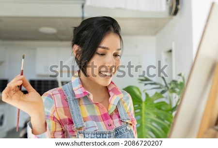 Hispanic Latina woman painting a picture at home, in her spare time