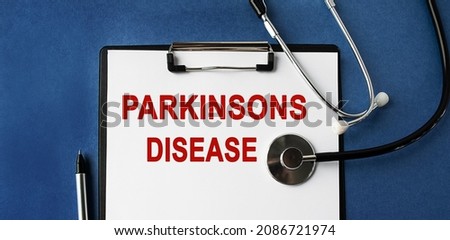 The inscription PARKINSONS DISEASE on the clipboard. Doctor's workplace. Top view on a blue background with a stethoscope. Medical topics.