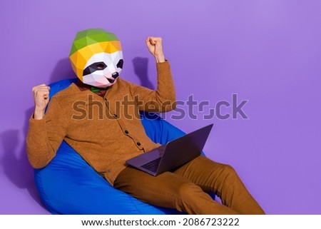 Photo of excited sloth face guy sit blue bag raise fists success wireless netbook isolated on purple color background