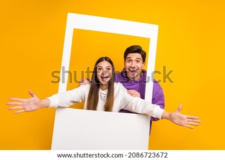 Portrait of two crazy carefree people make instant frame photo raise opened arms isolated on yellow color background