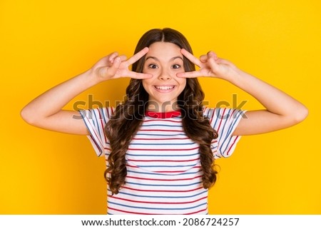 Photo of young happy excited smiling cheerful positive funky girl show v-sign on eyes isolated on yellow color background