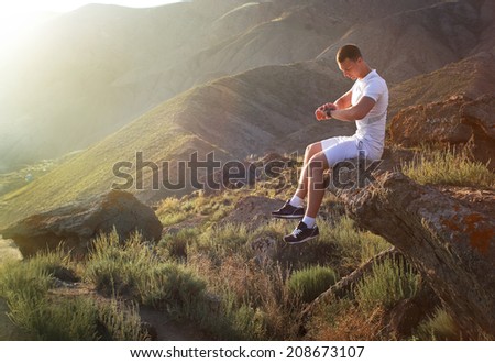 Young man in fitness clothing running along mountain 