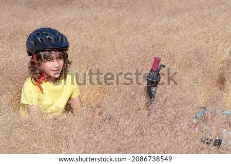 portrait of a smiling boy in safety helmet lying in a field with tall grasses
