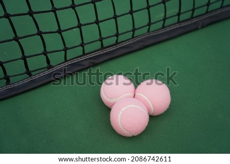 Tennis balls with tennis court and net in background.
