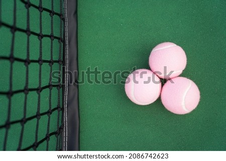 Tennis balls with tennis court and net in background.