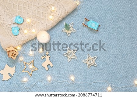 On a blue knitted blanket, shining garlands, wooden symbols of Christmas