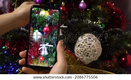 A female hand makes a photo of a Christmas elegant tree using a smartphone.Photo for social networks