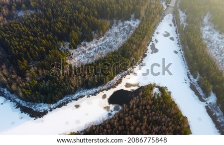 Aerial view of white snowy frozen river and forest