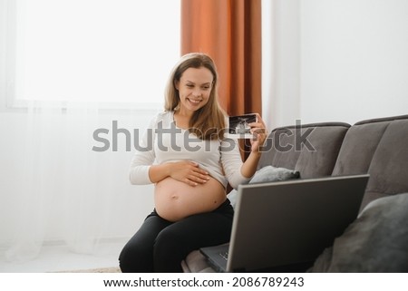 selective focus of cheerful pregnant woman showing ultrasound photos while having video call
