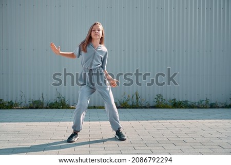 Dancing teen girl cool moving outdoors on urban background. Energetic cool young dancer showing hip hop dance on street