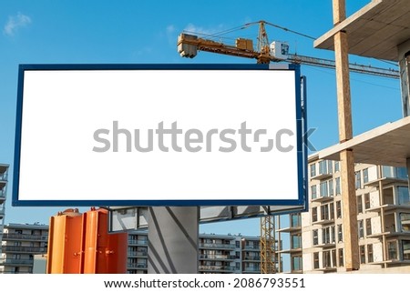 Blank white advertising billboard on the construction area with modern residential buildings in the background