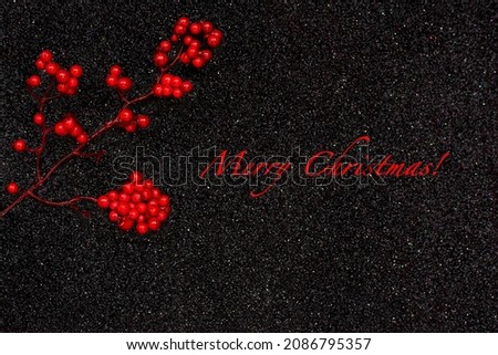 Christmas background. Red berries branch on a black shining background. View from above. Christmas greeting card. Selective focus.