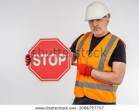 Danger from construction. Builder stops movement. Stop sign in foreman's hand. Stop sign in worker's hand. Man warns of danger. Builder forbids further movement. Metaphor of imposing restrictions