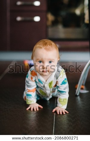 Baby boy crawling on the floor in nursery room at home. Baby health care and family concept.