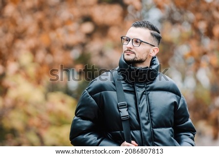 Man wearing fashionable clear glasses looking away autumn colors