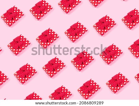Christmas red polka dot paper wrapped gift pattern on pink background, surprise present, minimal holiday symbol