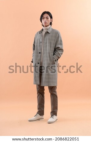 Fashion and style.full length body young handsome man wearing coat,sweater , pants in brown background

