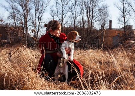 pretty young woman in red coat playing with dog outside in park, lifestyle people concept