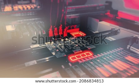 Digital technologies for automation of industry. Red neon lights illuminate Chip Components for automation test. SMT Concept: Production of high-tech computer boards on an automatic SMT machine. Royalty-Free Stock Photo #2086834813