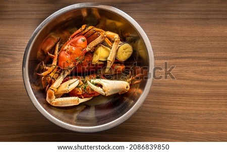 Overhead of a bowl with crabs cooking on a wooden background Royalty-Free Stock Photo #2086839850