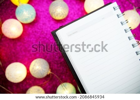 Empty notepad mockup and LED cotton balls decoration on pink bokeh background