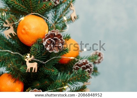 A Christmas tree decorated with orange tangerines, cones and wooden deer.