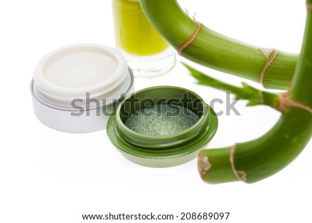 Green eyeshadow in a small compact displayed with a fresh bamboo sprout in a concept of natural cosmetics following the colours of nature anf organic plants