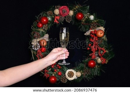 Christmas glass of sparkling wine in the hands of a girl against the background of a Christmas wreath. Christmas holiday concept. Christmas,New Year's holiday.selective focus. copy space.New Year card