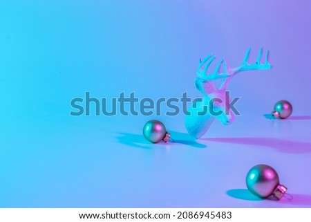 Christmas deer neon winter background. Minimal abstract xmas reindeer. Holiday decoration bauble ball on neon gradient backdrop. Minimal new year card
