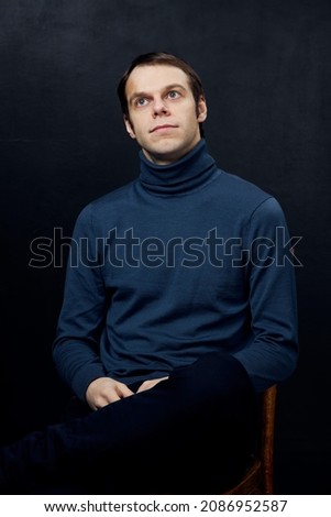 portrait of a young man in a blue sweater on a dark background