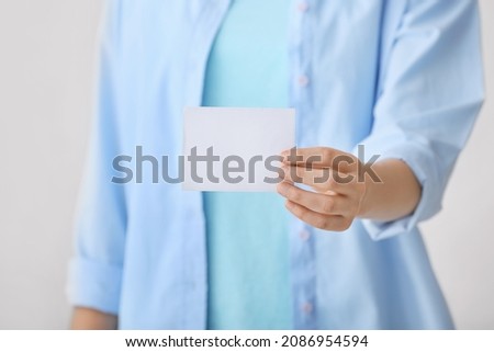 Woman with blank paper sheet on color background