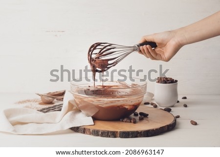 Woman cooking tasty melted chocolate on table in kitchen
