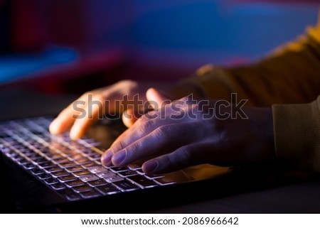 Male hands are typing on a laptop keyboard, a man works, develops a business, studies, plays a computer game at night. Close-up view. Royalty-Free Stock Photo #2086966642